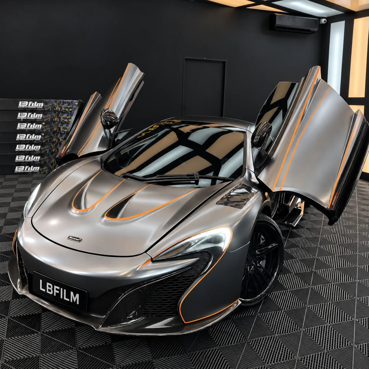 Silver McLaren with raised doors and orange accents in the LBFILM workshop